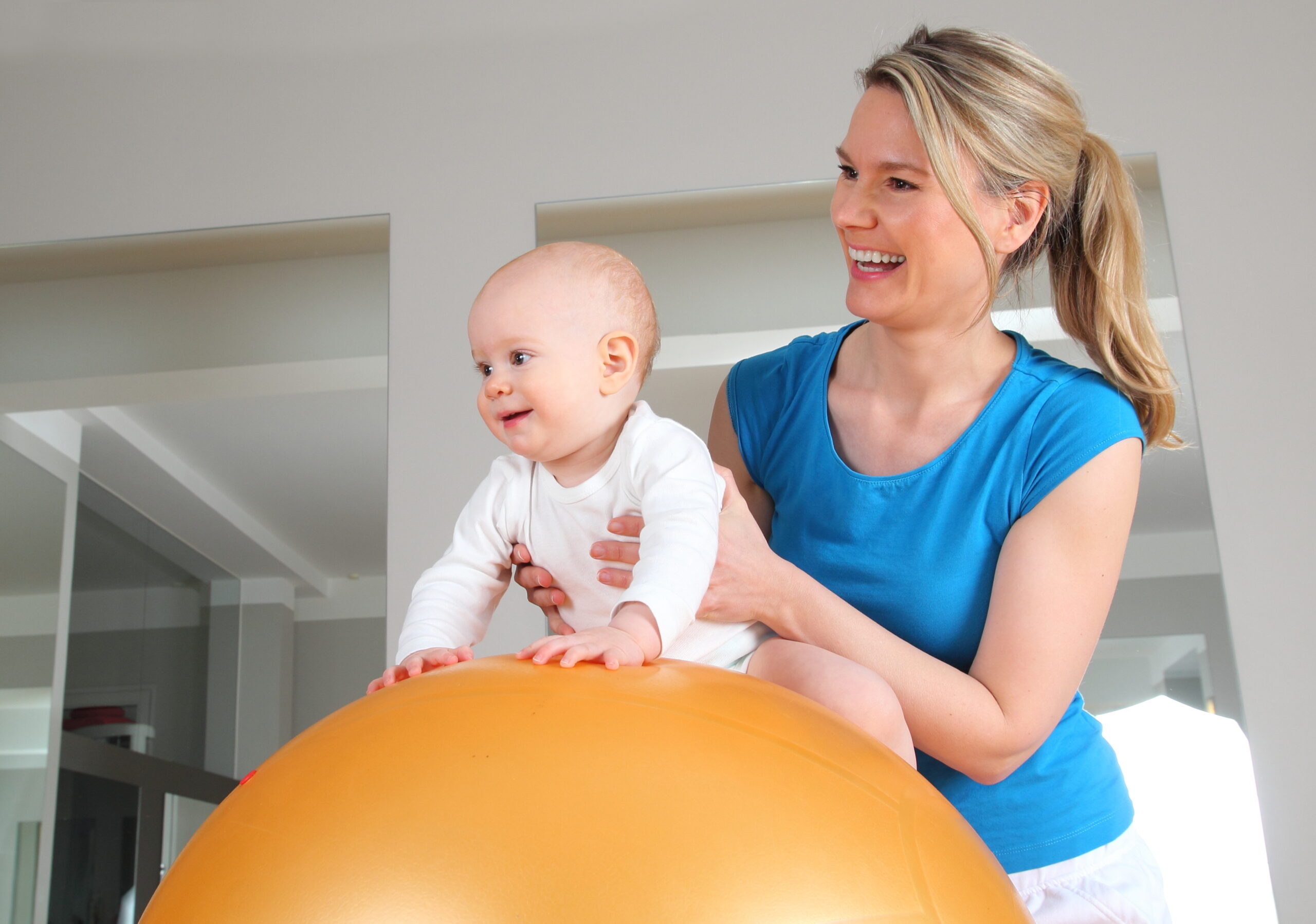 baby with IDD and a developmental interventionist helping the baby on a medicine ball