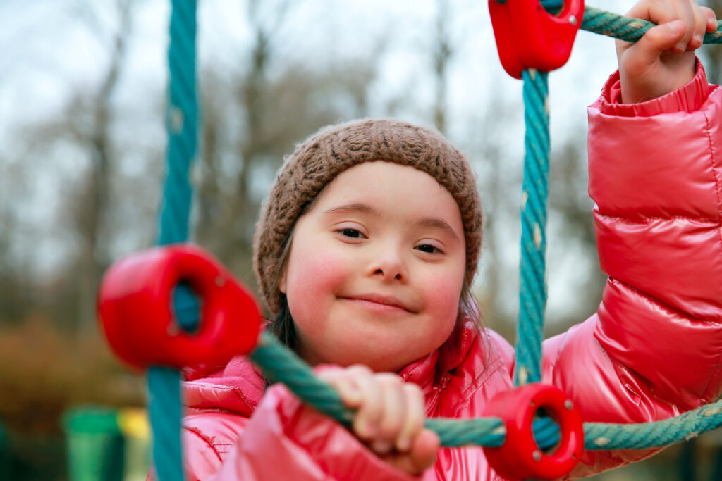 IDD youth playing on playground smiling 