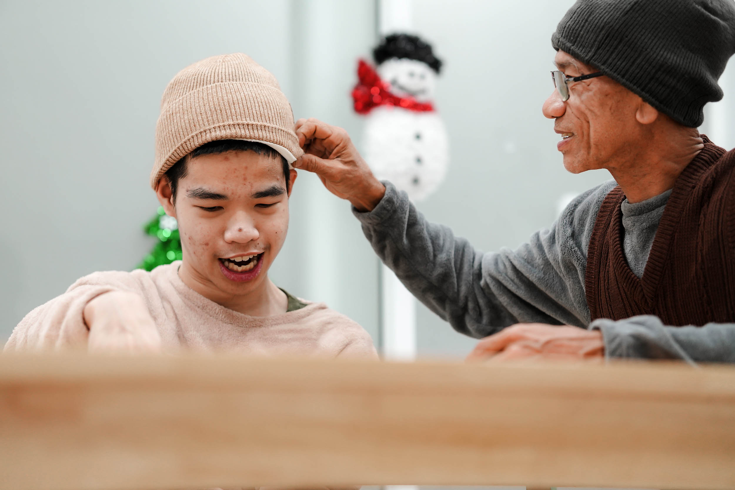 home provider adjusting young man with disability's beanie