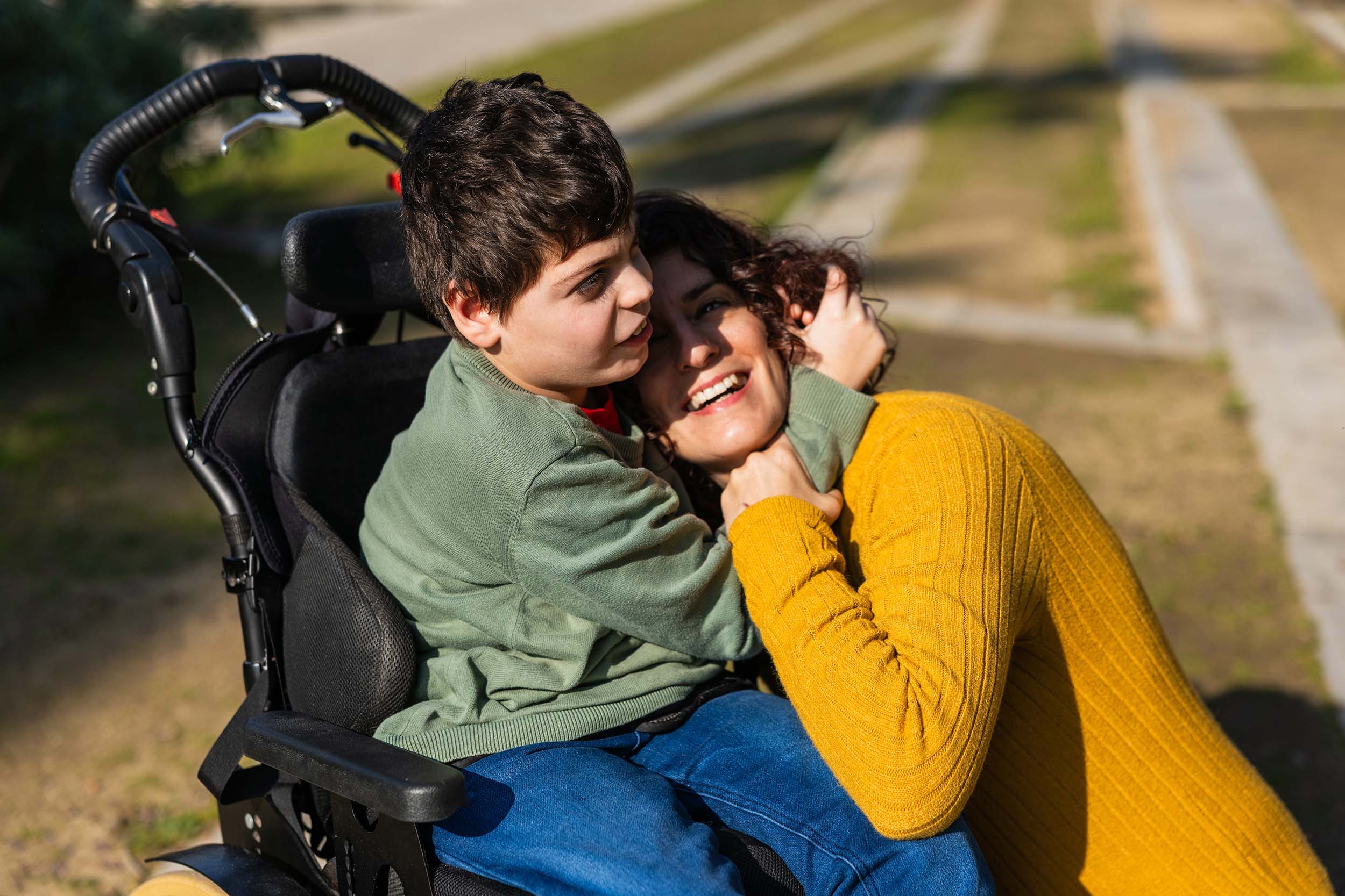 Mother hugging her son, who is in a wheelchair, who is hugging her back.
